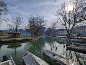 A view of the canal in Annecy with boats and trees along each side. You can see the Lover's Bridge in the distance