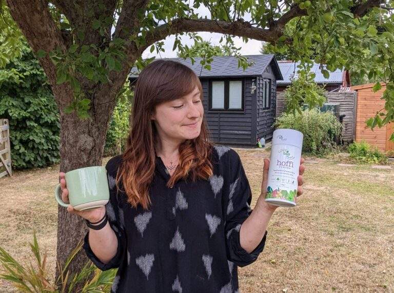 Alice staring lovingly at a tub of SuperBioBoost's superfood supplement whilst holding a mug in her other hand