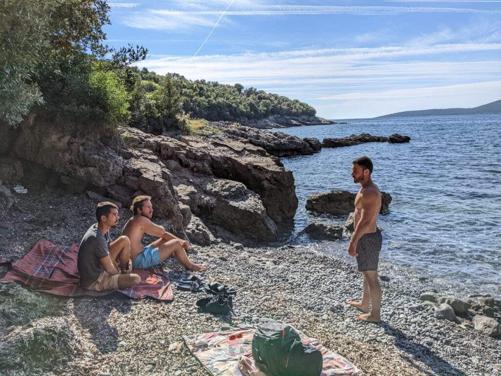 Three men chatting on the beach in a secret cove near Blue Horizon beach on Lustica peninsula