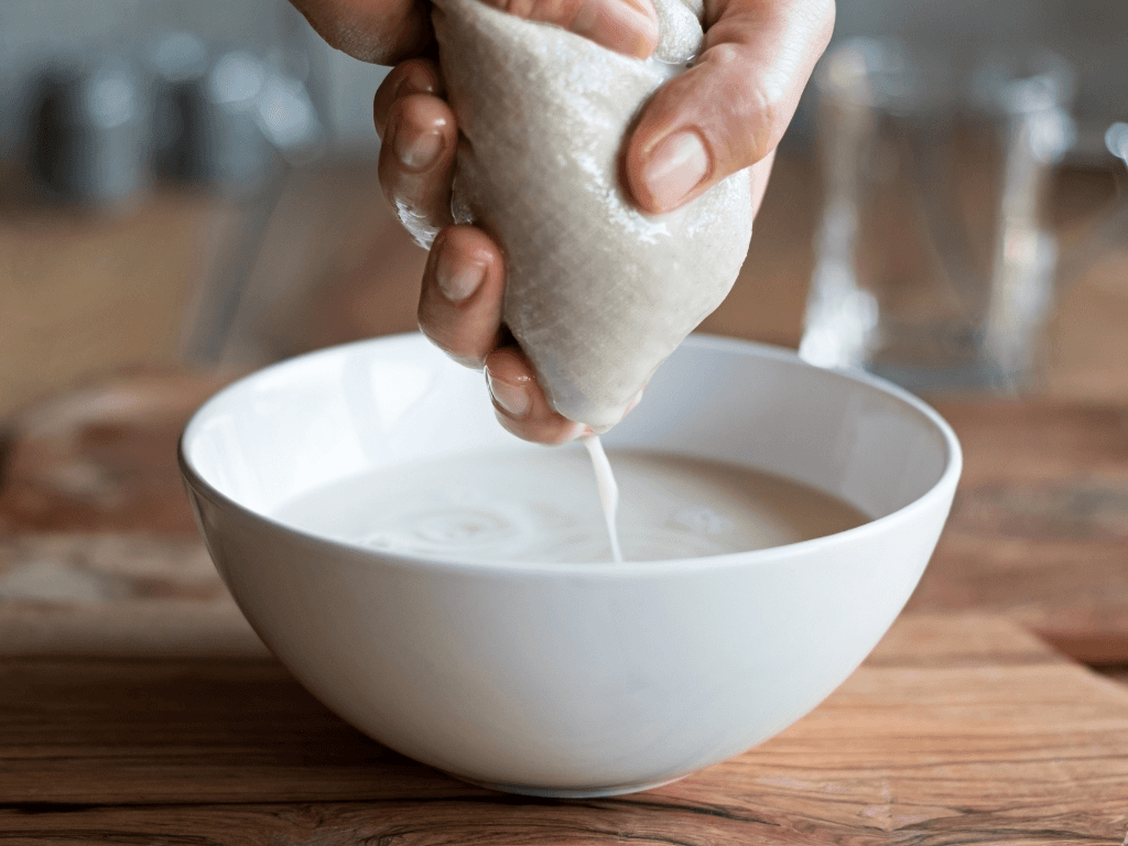 Squeezing out the nut milk into a bowl using a nut milk bag